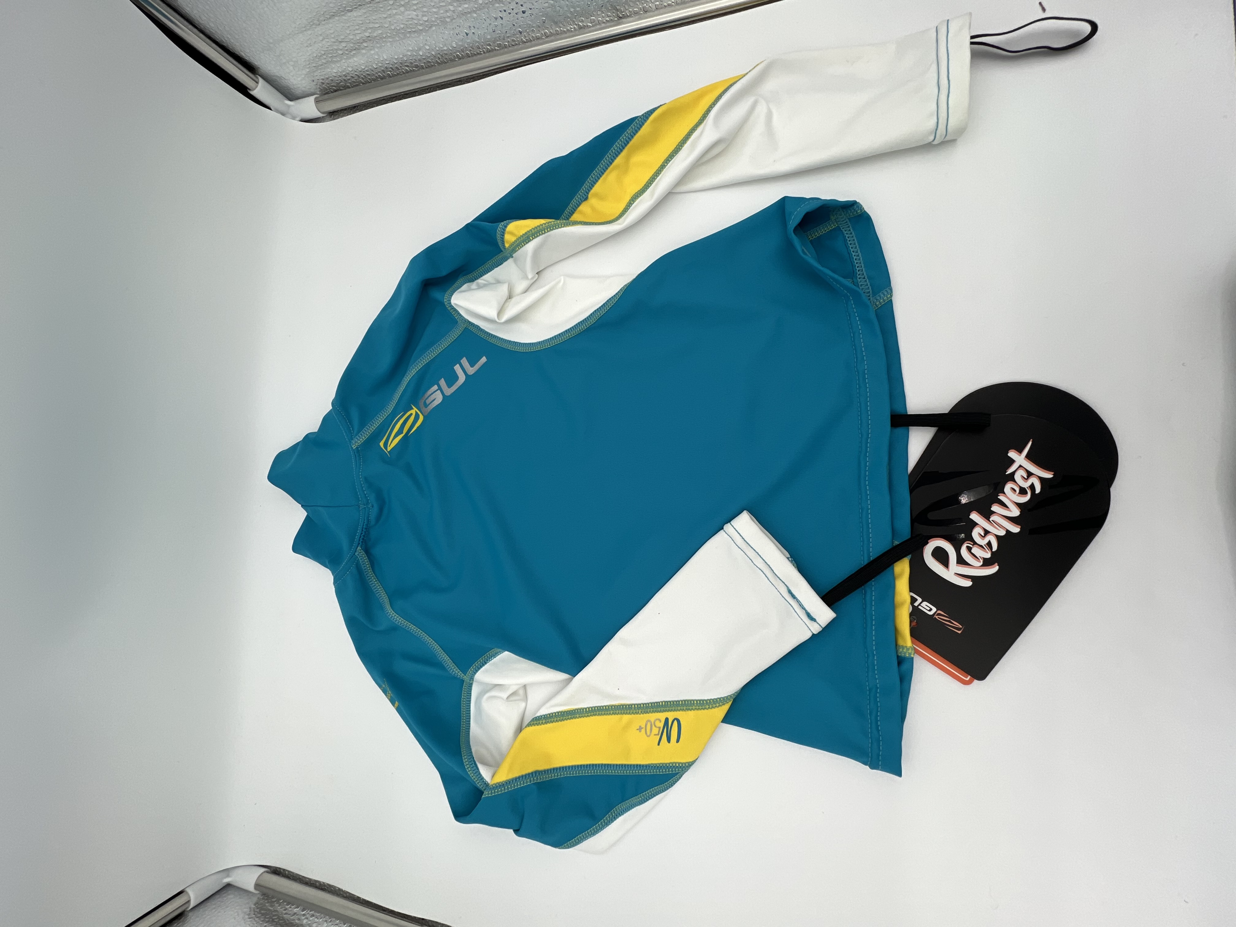 Billede fra myndighedens meddelelse af det tilbagekaldte produkt GUL JR , langærmet rashguard cp/white. Årsag: OVERTRÆD.