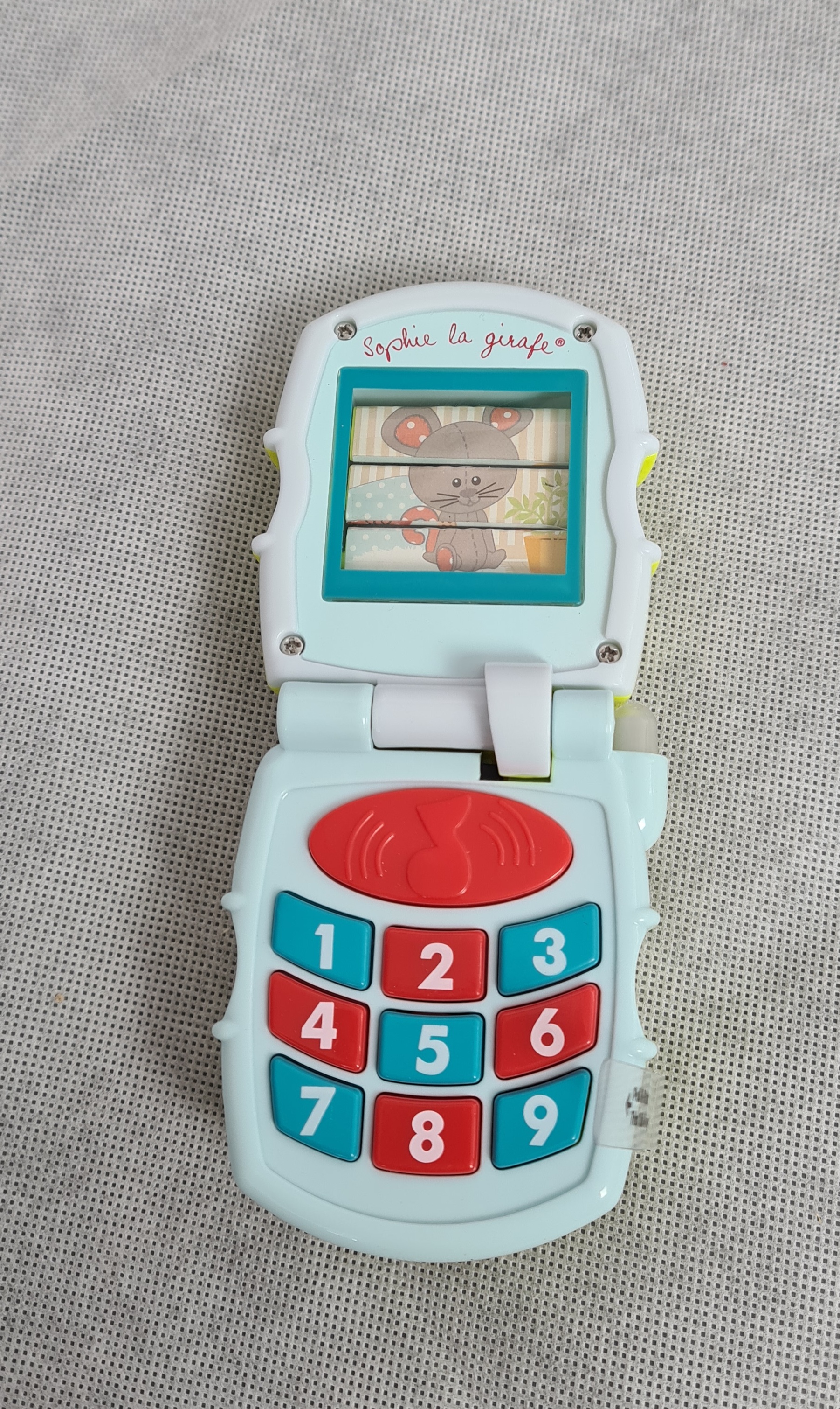 Billede fra myndighedens meddelelse af det tilbagekaldte produkt Baby Mobil - Musical Phone Fra Sophie Giraf. Årsag: OKTILTAG.